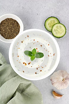 Indian raita sauce with yogurt, cucumber and herbs on a gray background. Top view. Indian food. Greek tzatziki sauce.