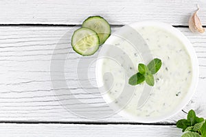 Indian raita sauce with yogurt, cucumber and herbs on a white background. Top view. Indian food. Greek tzatziki sauce.