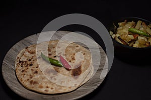 Indian recipe paratha with fried potato with green and red chili on black copy space background.