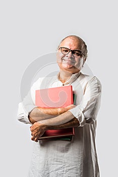 Indian retired senior or old man reading book or newspaper