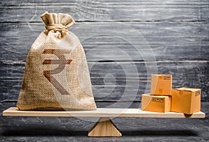 Indian rupee INR symbol money bag and a bunch of boxes on scales. Trade exchange balance. Import and export, economic processes. photo