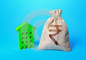 Indian rupee money bag and green Resident building. Investment in green technologies. Reduced emissions and improved energy