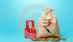 Indian rupee money bag and red padlock. Blocking bank accounts and seizing assets. Freezing of pension savings. Cash flow