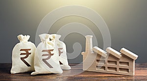 Indian rupee money bags and industrial factory plant. Privatization and purchase of industrial complexes. Investment