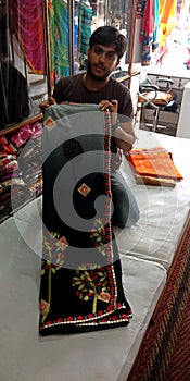 an indian sari seller presenting women stuff at showroom