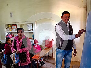 an indian school class teacher writing on chalkboard during class in india January 2020
