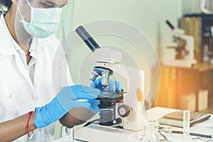 Indian Scientist man look into Microscope research in science laboratory. Asian biochemistry scientist using microscope in