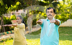 Indian senior couple doing yoga or stretching at park during morning - concept of active lifestyle, training session and
