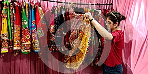 an indian shopkeeper girl holded traditional women outfits at garment store