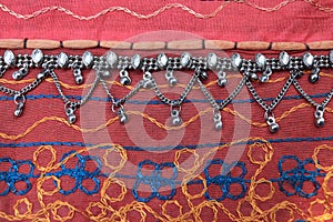 Indian silver anklets on the background of a traditional patchwork carpet. in indian background