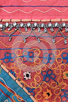 Indian silver anklets on the background of a traditional patchwork carpet. in indian background