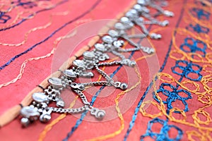 Indian silver anklets on the background of a traditional patchwork carpet. in indian background