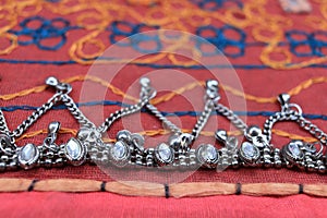 Indian silver anklets on the background of a traditional patchwork carpet. in indian background