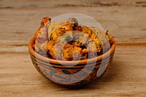 Indian snack pakora in a bowl on wooden background
