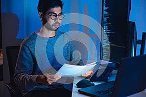 Indian software development working on coding computer screen and flowchart at night in modern office