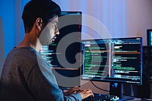 Indian software development working on coding computer screen and flowchart at night in modern office