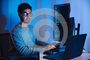 Indian software development working on coding computer screen and flowchart at night in modern office