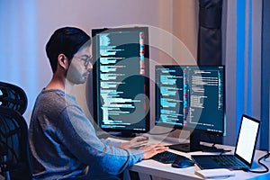 Indian software development working on coding computer screen and flowchart at night in modern office