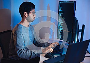 Indian software development working on coding computer screen and flowchart at night in modern office