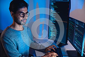 Indian software development working on coding computer screen and flowchart at night in modern office