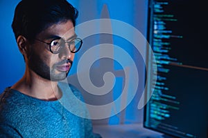 Indian software development working on coding computer screen and flowchart at night in modern office