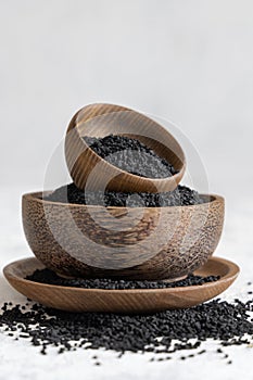 Indian spice Black cumin nigella sativa or kalonji seeds in wooden bowls on white table close up