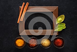 Indian spices in bowls and empty wooden frame for text