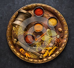 Indian spices, spicy and seasoning in bowls and in a mortar on a brass tray,