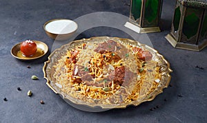 Indian spicy Beef Biryani with raita and gulab jamun Served in a dish side view on grey background