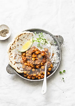 Indian spicy chickpeas curry with rice and naan bread in pan on light background, top view photo