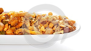 Indian spicy snacks Namkeen - All in one` in white ceramic oval bowl, having peanut, corn flakes, sweet pea, pulses, cash