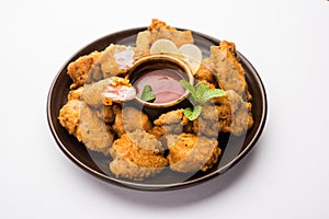 indian starter chicken pakora or pakoda or fritter served with tomato ketchup