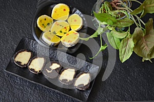 Indian sweet food mithai. Milk cake, chocolate rolls, and pineapple rolls with black dishes and black background. Milk products.