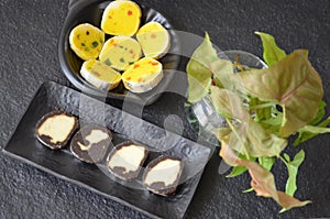 Indian sweet food mithai. Milk cake, chocolate rolls, and pineapple rolls with black dishes and black background. Milk products.