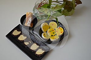 Indian sweet food mithai. Milk cake, chocolate rolls, and pineapple rolls with black dishes and white background. Milk products.