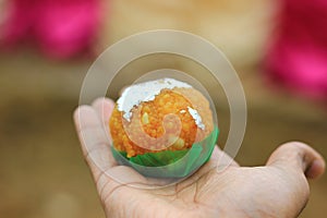 An indian sweet laddoo in hand with selective focus and shallow depth of field