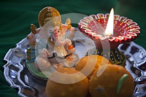 Indian sweet laddu with a prayer lamp and Ganesha statue