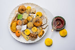 Indian sweets or Mithai for diwali festival with oil lamp or diya and gift box