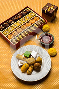 Indian sweets or Mithai for diwali festival with oil lamp or diya and gift box