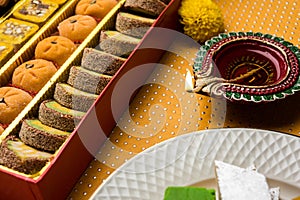 Indian sweets or Mithai for diwali festival with oil lamp or diya and gift box
