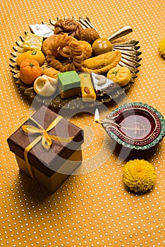 Indian sweets or Mithai for diwali festival with oil lamp or diya and gift box