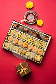 Indian sweets or Mithai for diwali festival with oil lamp or diya and gift box photo