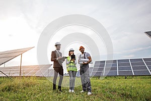 Indian technician standing at solar farm with two inspectors