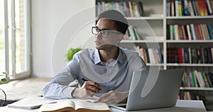 Indian teen student guy in glasses studying in university library