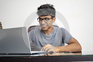 Indian teenager working on his laptop. Concentration and work from home concept