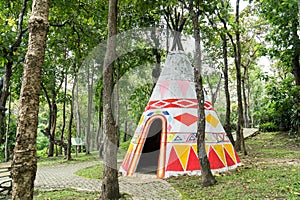 Indian teepee tent in public park with tree plant background. Colorful native american indian tipi painted in forest