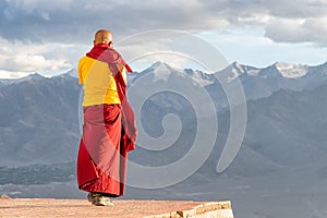 Indian tibetan monk lama in red and yellow color clothing standing in front of mountains