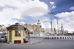 People walking beside Skara road with traffic near Kalachakra Stupa Roundabout at Leh Ladakh village in Jammu and Kashmir, India