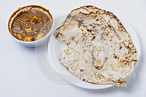 Indian traditional food, chapati or naan roti with paneer butter masala curry in a bowl on white background