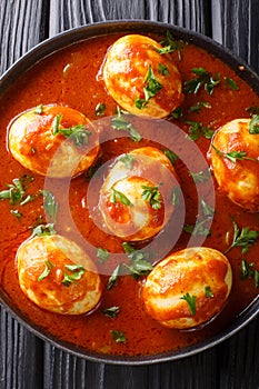 Indian traditional food curry eggs in spicy sauce close-up in a plate. Vertical top view